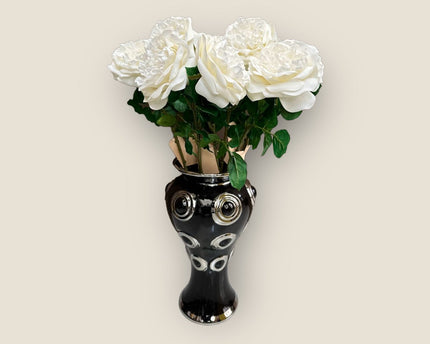 Een prachtige zwarte vaas met 10 grote, witte bloemen.